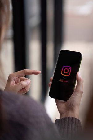 CHIANG MAI, THAILAND - AUG 08, 2023: A woman holds Apple iPhone 14 Pro Max with Instagram application on the screen at cafe. Instagram is a photo-sharing app for smartphones.のeditorial素材