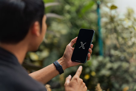 CHIANG MAI, THAILAND - July 28, 2023: Man holding a Apple iPhone with Twitter on the screen. Twitter is a social media online service for microblogging and networking communication.のeditorial素材