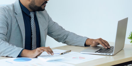 Businessman using a calculator to calculate numbers on a companys financial documents, analyzing historical financial data to plan how to grow the company. Financial concept.の写真素材