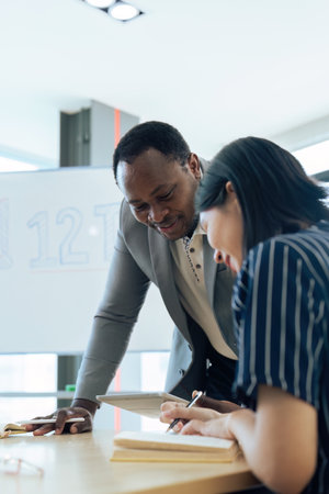 Mature professor talking to his student while assisting her on a class at the university