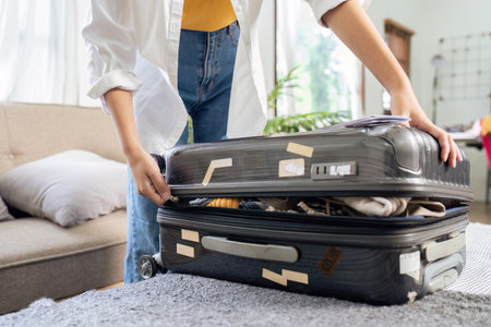 Young woman sit in floor and preparation suitcase for travelling at weekend tripの写真素材