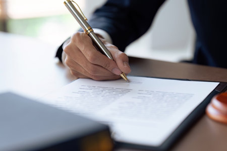 businessman with a suit signing a document with his pen by writing down his signatureの写真素材