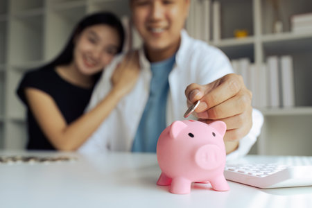 Man and woman couple smiling confident insert coin on piggy bank at homeの写真素材