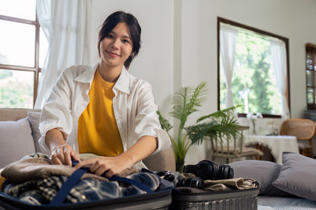 Young woman sit in floor and preparation suitcase for travelling at weekend tripの写真素材