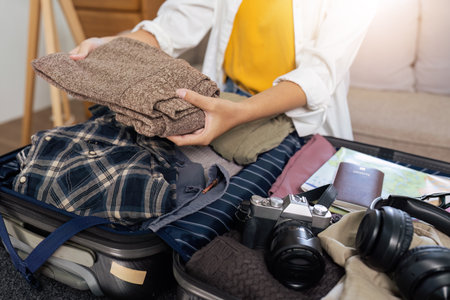 Close up young woman sit in floor and preparation suitcase for travelling at weekend tripの写真素材