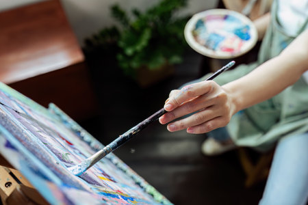Female artist hold color palette and paintbrush for painting during hobby workshopの写真素材
