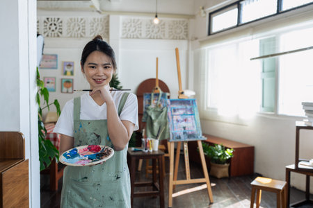 young man holding painter palette at artist studio looking at the camera