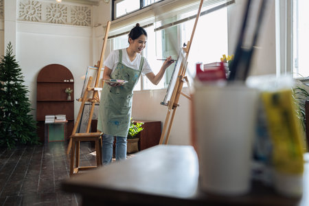 Female artist hold color palette and paintbrush for painting during hobby workshopの写真素材