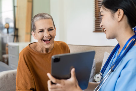 Asian nurse showing health checkup report to older and giving advice. Home nursing and healthcare caregiver conceptの写真素材