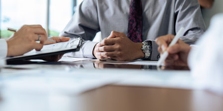 Focused executive businessman client clasped hands negotiating, thinking, making decision sitting at...