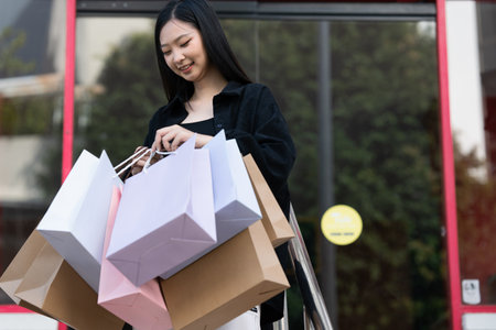 Young asian woman in shopping. Fashion woman in black with shopping bag walking out store after shopping. Black fridayの写真素材
