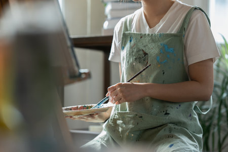 Female artist hold color palette and paintbrush for painting during hobby workshopの写真素材