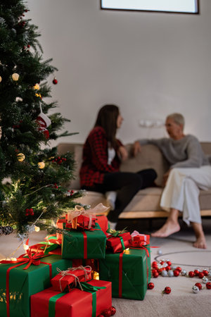 Beautiful Christmas gift boxes on floor near Christmas tree and have people background in roomの写真素材