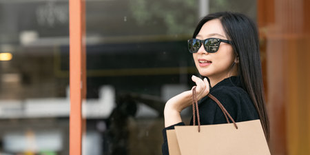 Young asian woman in shopping. Fashion woman in black with shopping bag walking around the city after shopping. Black fridayの写真素材