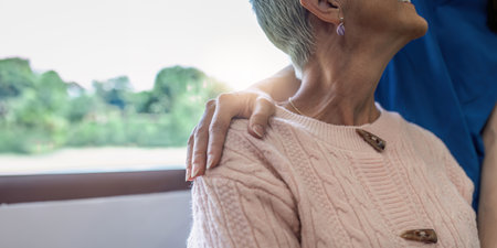 Caregiver or nurse put hands around shoulder of elderly patient for supportの写真素材