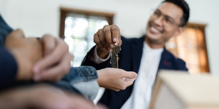 Happy real state agent giving new house key to a young couple. Real estate conceptの写真素材