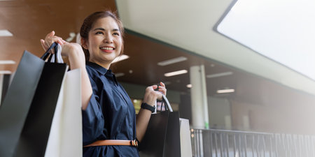 Young asian woman in shopping. Fashion woman in black with shopping bag walking around the city after shopping. Black fridayの写真素材