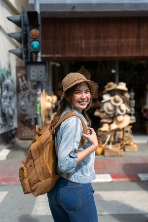 Young female tourist walking across the street and looking at camera while traveling in local market