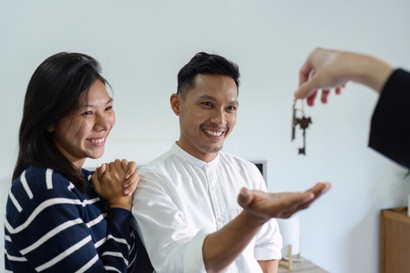 Happy real state agent giving new house key to a young couple. Real estate conceptの写真素材