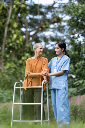 Nurse or caregiver help elderly walk by using walker and elderly touching caregiver handの写真素材