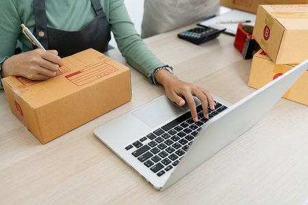 Asian woman using laptop to prepare for delivery to customer. e-business conceptの写真素材