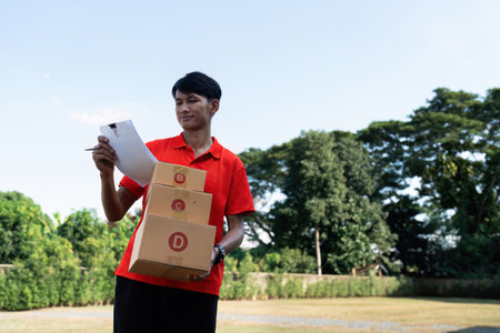 Young delivery man checking detail about parcel. Male postman courier with shopping package. Shipment conceptの写真素材