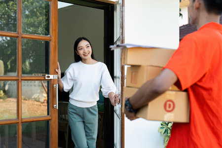 Young Asian cute girl receiving boxes from postman at the door. Delivery conceptの写真素材
