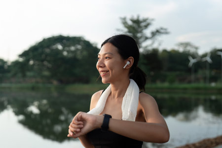 Sport young woman looking at smartwatch on her wrist, tracking fitness activity during training outdoorsの写真素材