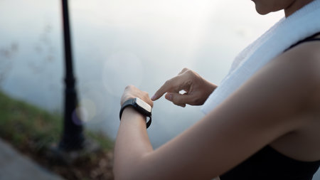 Sport young woman looking at smartwatch on her wrist, tracking fitness activity during training outdoorsの写真素材