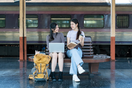 Woman traveler with backpack using laptop to planning vacation on holiday relaxation at the train stationの写真素材