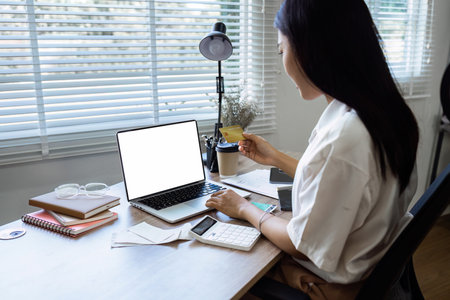Young woman makes a purchase on the Internet on the laptop with credit cardの写真素材