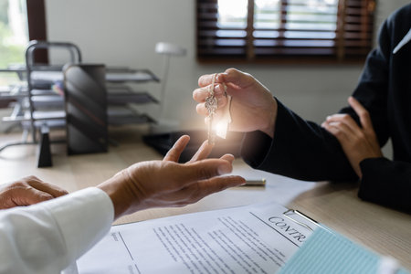 Real estate agent give the customer the keys after signing contract success with Home Loan and Home Insurance in the Officeの写真素材
