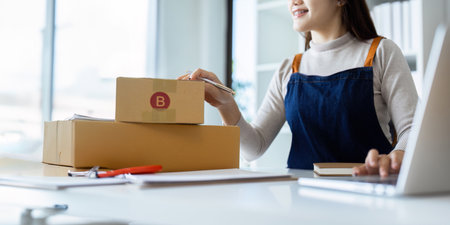 Young business woman entrepreneur online shipment business is preparing packages to send to...