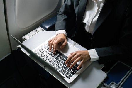 businesswoman flying and working in an airplane in first class, sitting inside an airplane using laptopの写真素材