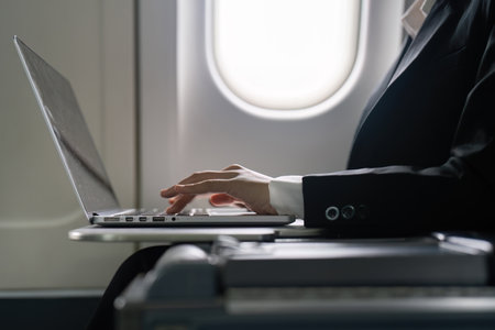 businesswoman flying and working in an airplane in first class, sitting inside an airplane using laptopの写真素材