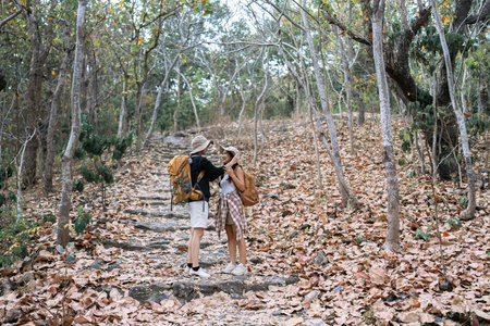 Happy LGBT Lesbian couple Travelers Hiking with Backpacks in forest Trail. LGBT Lesbian Couple...