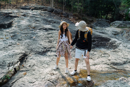 Happy LGBT Lesbian couple Travelers Hiking with Backpacks in waterfall Trail. LGBT Lesbian Couple Hikers with backpacks walks in mountains in vacationの写真素材