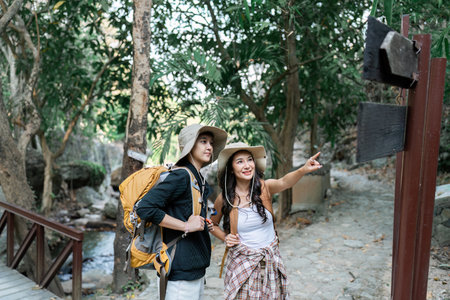 Happy LGBT Lesbian couple Travelers Hiking with Backpacks in waterfall Trail. LGBT Lesbian Couple Hikers with backpacks walks in mountains in vacationの写真素材