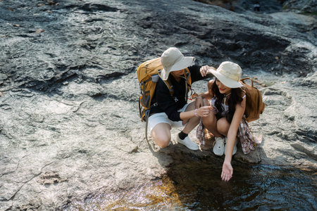 Happy LGBT Lesbian couple Travelers Hiking with Backpacks in waterfall Trail. LGBT Lesbian Couple Hikers with backpacks walks in mountains in vacationの写真素材