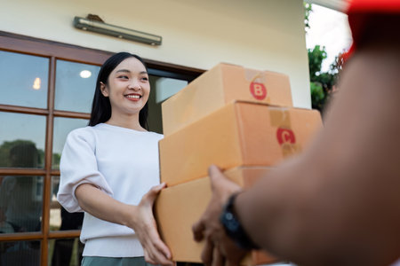 Asian young delivery man delivering package to female customer at homeの写真素材