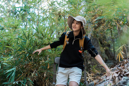 LGBTQ backpacker traveling alone in forest. Attractive male traveler walking in nature wood during...