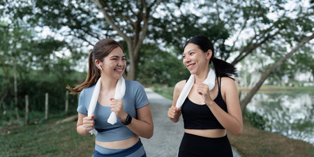 Two happy women going for sunrise running. Women in track suits running at parkの写真素材