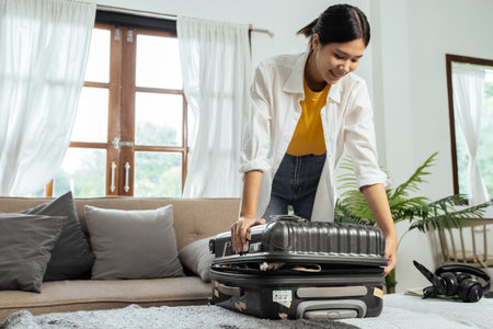 Young woman sit in floor and preparation suitcase for travelling at weekend tripの写真素材