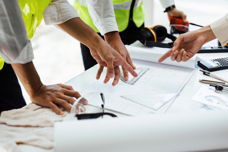 Team of engineers reviewing blueprints Sketch of a new construction project with engineering tools...
