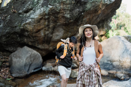 Happy LGBT Lesbian couple Travelers Hiking with Backpacks in waterfall Trail. LGBT Lesbian Couple...
