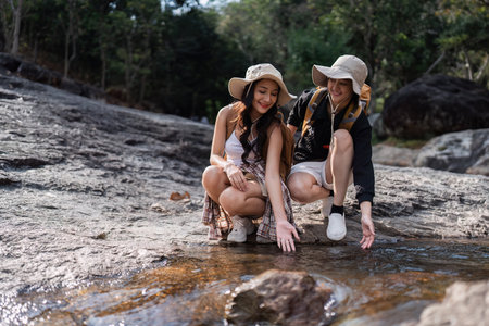 Happy LGBT Lesbian couple Travelers Hiking with Backpacks in waterfall Trail. LGBT Lesbian Couple Hikers with backpacks walks in mountains in vacationの写真素材