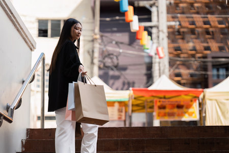 Young asian woman in shopping. Fashion woman in black with shopping bag walking around the city after shopping. Black fridayの写真素材