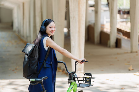 Asian young businesswoman bike to work for eco friendly green energy and listen music with headphone while commuting in city. Eco friendlyの写真素材