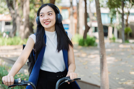 Asian young businesswoman bike to work for eco friendly green energy and listen music with headphone while commuting in city. Eco friendlyの写真素材