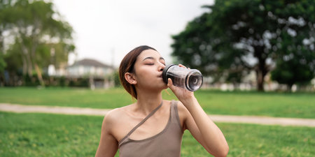 Drinking water, fitness and exercise woman after sports run and training in nature. Workoutの写真素材